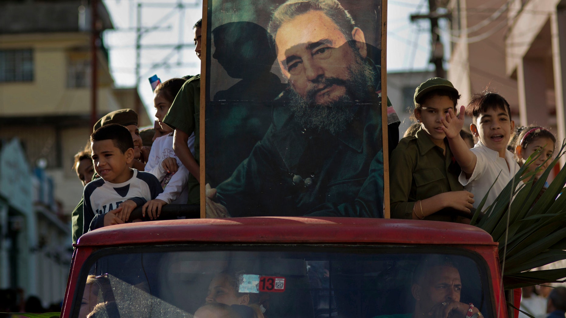 Children ride in the bed of a truck with a framed image of Fidel Castro, in Regla, Cuba, Thursday, Jan. 8, 2015.