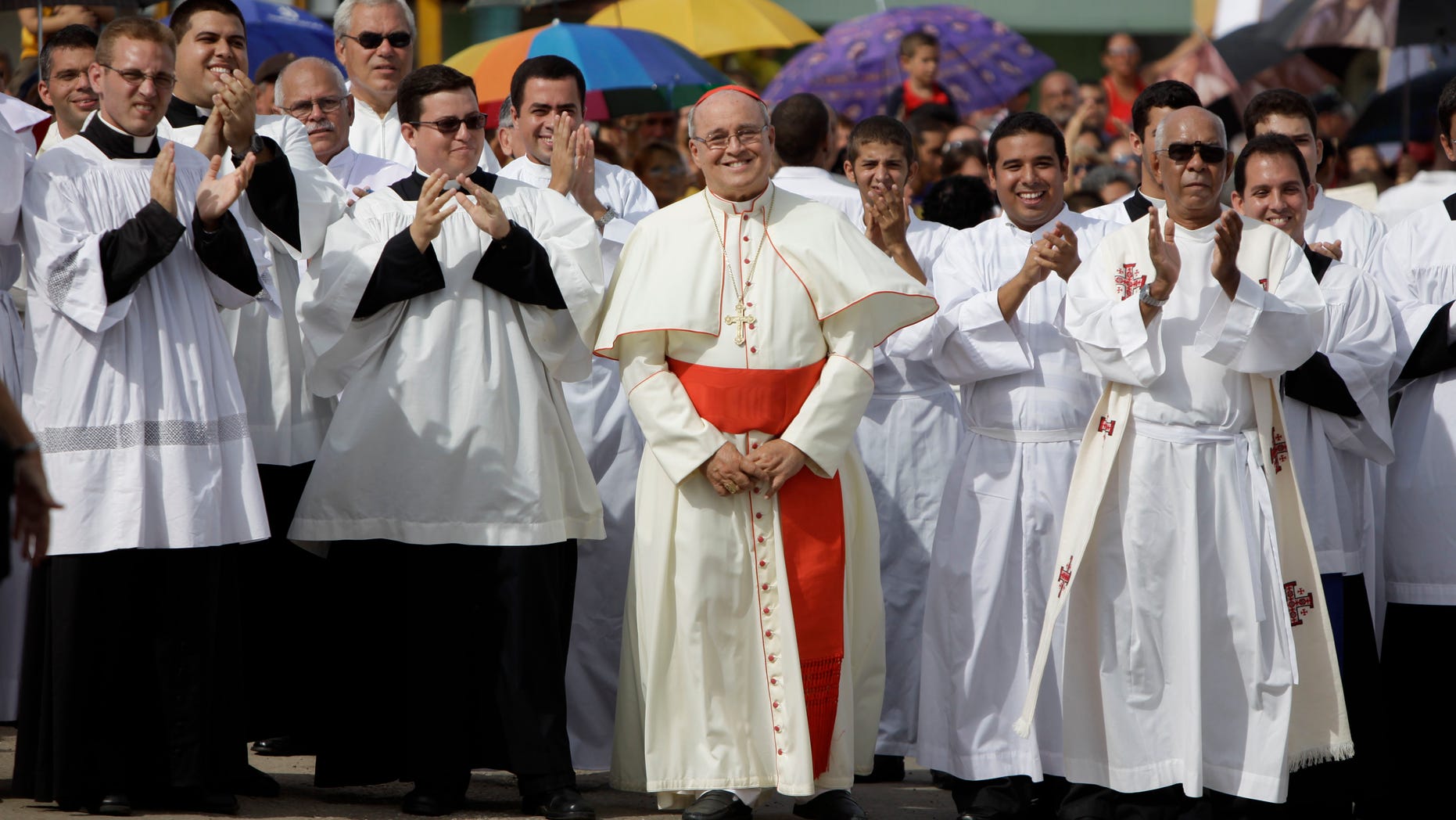 FILE - In this Sept. 4, 2011 file photo, Cuba's Cardinal Jaime Ortega, center, smiles as he waits for the Virgin of the Copper Charity during a procession in Madruga, Cuba. Ortega, who oversaw a warming of relations with the Communist government and played a role in the secret negotiations that led to U.S.-Cuba detente, has stepped down, the Vatican said on Tuesday, April 26, 2016. (AP Photo/Javier Galeano, File)