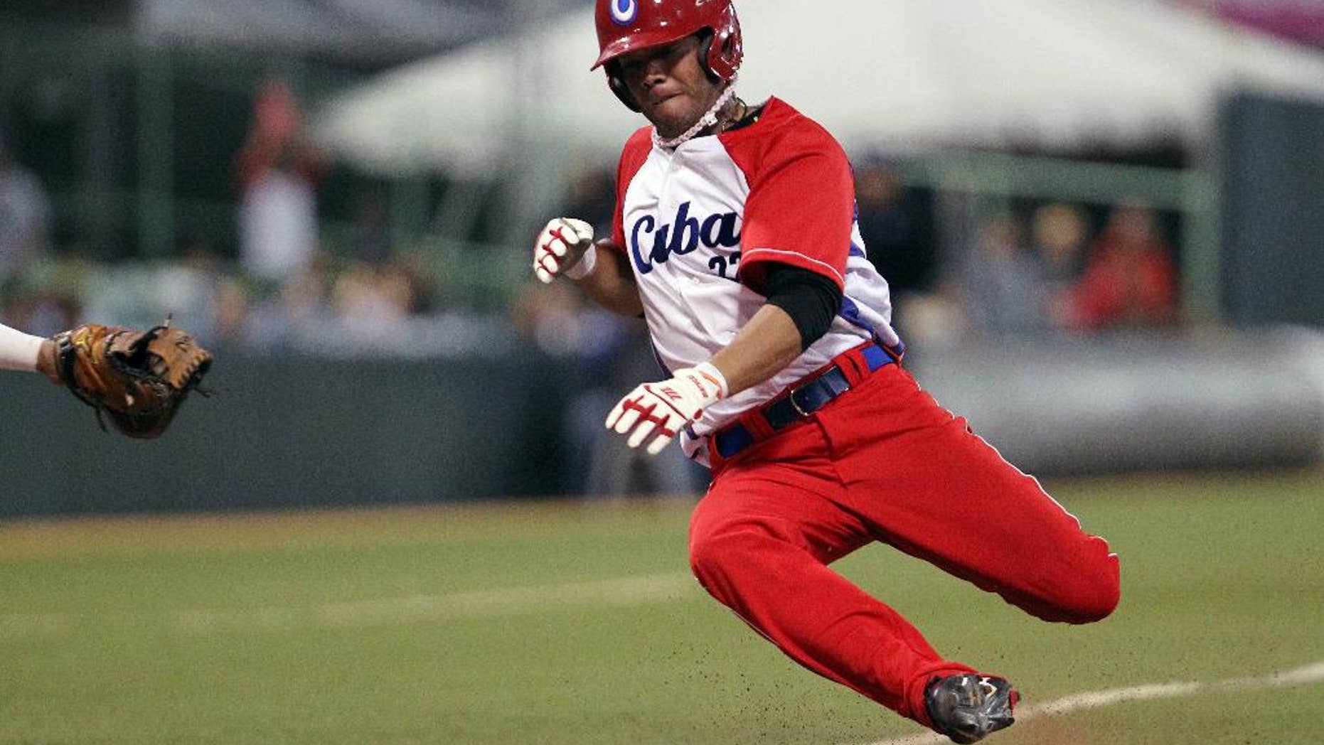 FILE - In this Feb. 7, 2015 file photo, Cuba’s Yadiel Hernandez slides safe at the home plate during a Caribbean Series baseball semifinal game against Venezuela in San Juan, Puerto Rico. Cuba is confirming that two baseball players, including Hernandez, have defected while in the United States for a series of friendly games against U.S. collegians. (AP Photo/Ricardo Arduengo, File)