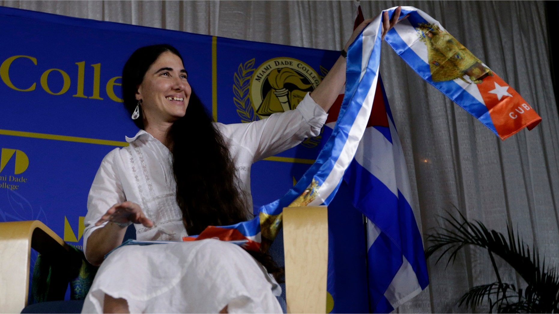 Blogger and activist Yoani Sanchez, of Cuba, holds up a gift given to her in the colors of the Cuban flag before speaking at the Freedom Tower of Miami Dade College, Monday, April 1, 2013, in Miami. Sanchez has gained thousands of followers worldwide for her candid descriptions of modern life in Cuba on her blog Generation Y. (AP Photo/Lynne Sladky)