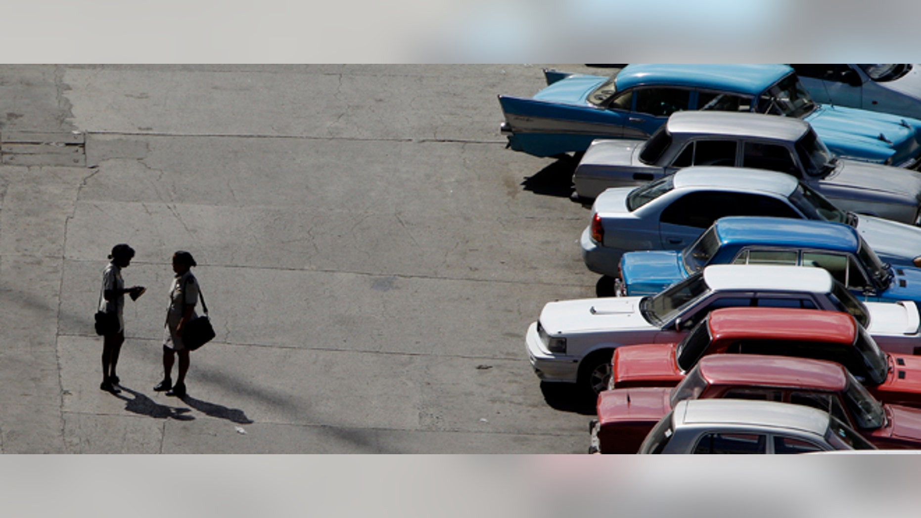 Sept 28: Two customs officers speak in a lot lined with cars in Havana, Cuba, The country legalized the sale and purchase of automobiles for all citizens on Wednesday.