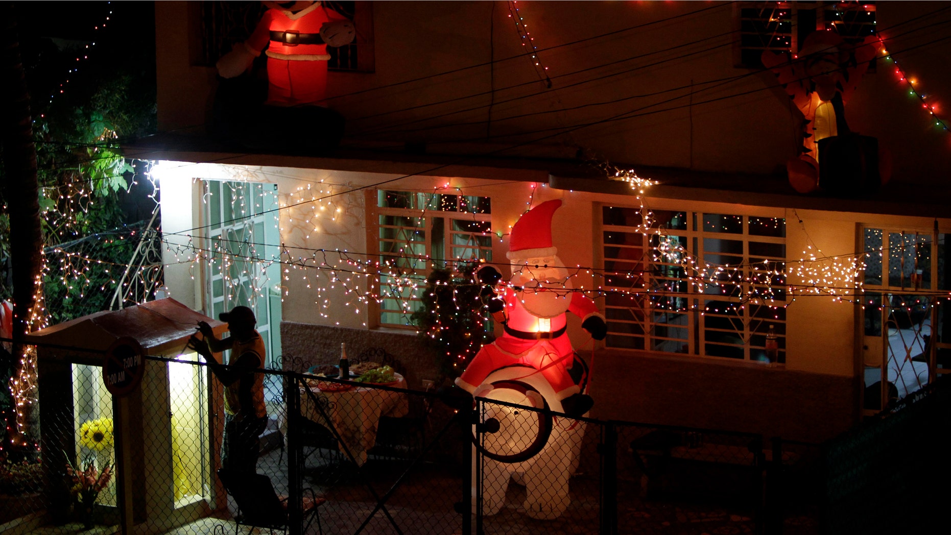 Antonio Alarcon opens the door to a shrine for the Virgin of Charity outside his home decorated in Christmas lights on Christmas Eve in Havana, Cuba, late Saturday Dec. 24, 2011. Cuban faithful celebrating Christmas say they have plenty to cheer this year as they prepare for the arrival of Pope Benedict XVI, the first visit by a pontiff to the Communist-run island since John Paul II's historic tour nearly 14 years ago. The visit, expected in March, coincides with the 400th anniversary of Cuba's patron saint and follows years of lobbying by Roman Catholic officials on the island. (AP Photo/Franklin Reyes)