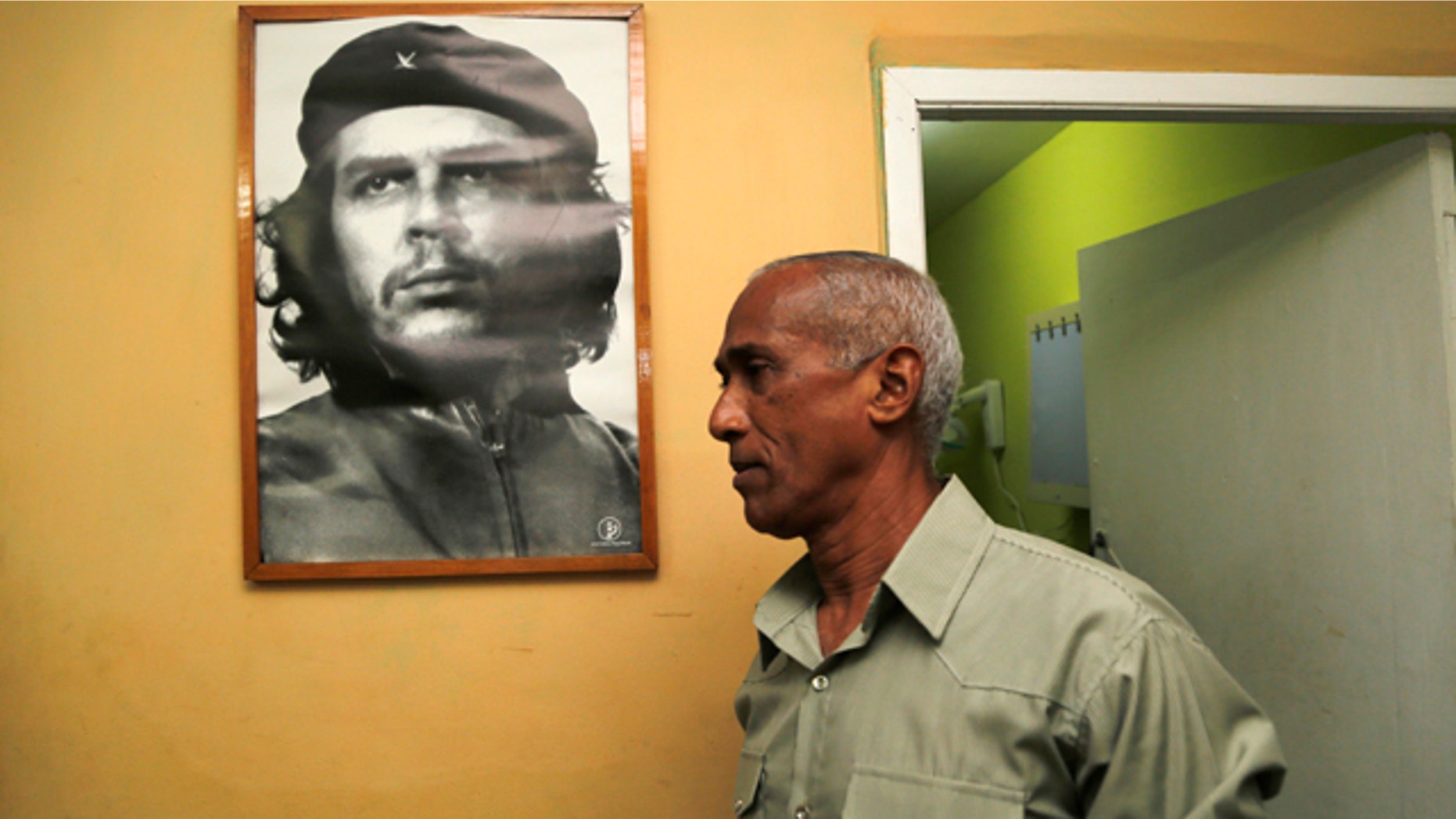 April 19, 2015: Dissident and candidate Hildebrando Chaviano walks beside a portrait of revolutionary leader Che Guevara before casting his ballot during Cuba's municipal elections at a polling station in Havana. (AP Photo/Desmond Boylan)