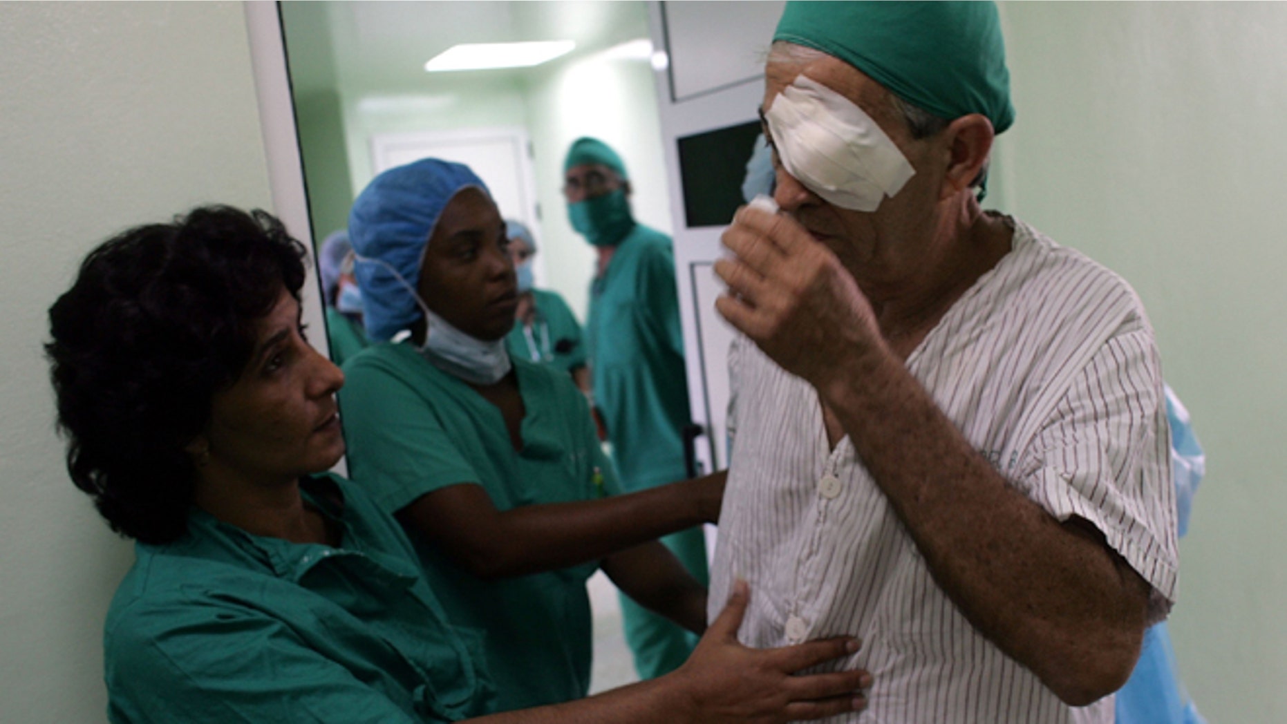 HAVANA - SEPTEMBER 12: Doctors help a patient after he had eye surgery performed by doctors participating in "Operacion Milagro" (Operation Miracle) September 12, 2006 at Pando Ferrer hospital in Havana, Cuba. The program is a joint health care program setup between Cuba and Venezuela which offers free eye care in Cuban hospitals for people living in Latin America and the Caribbean. (Photo by Joe Raedle/Getty Images)