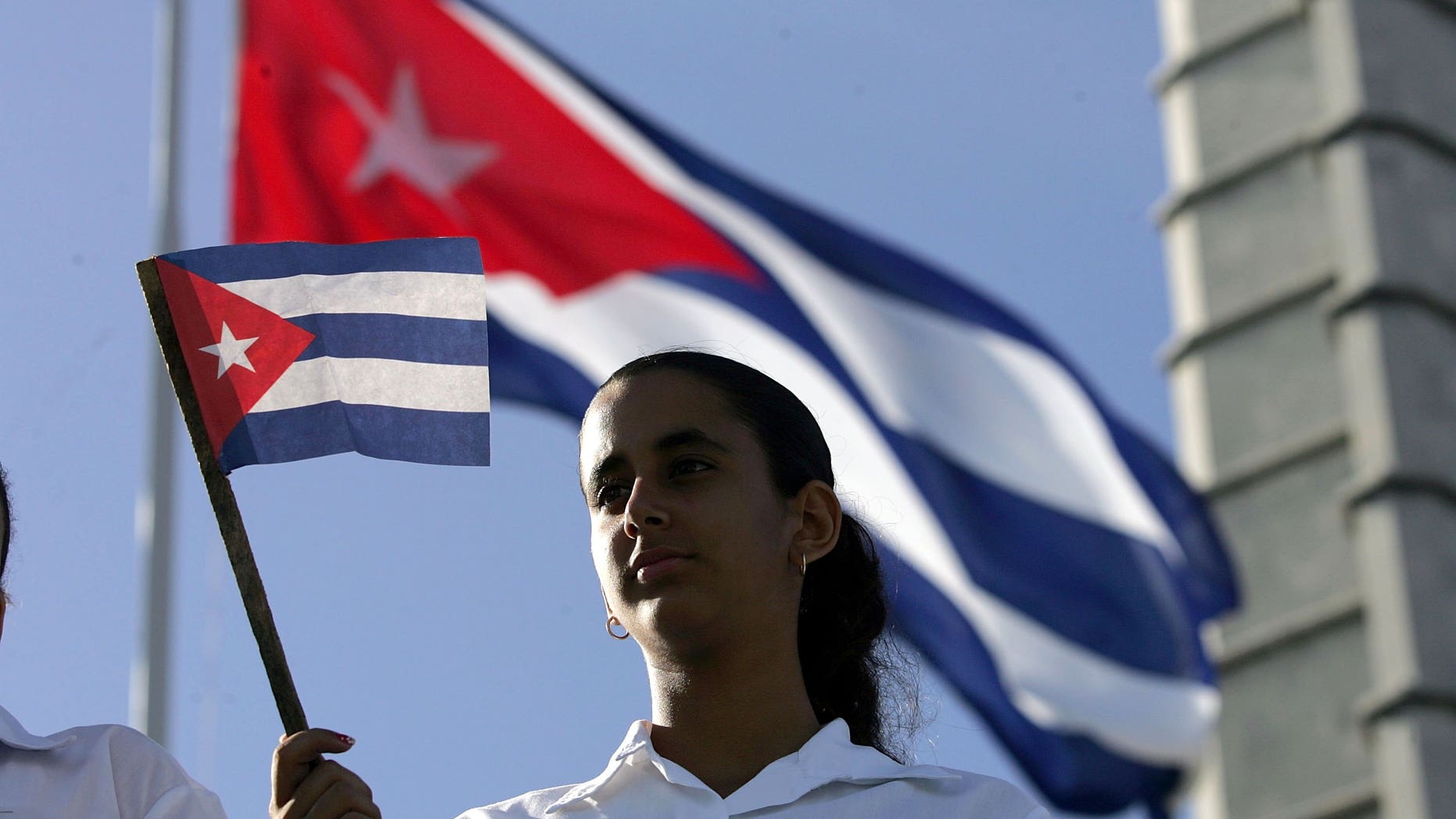 HAVANA, CUBA - DECEMBER 02: A young women waves a Cuban flag in Havana's Revolution Square during the 50th anniversary celebration of the forming of Cuba's Revolutionary Armed Forces December 2, 2006 in Havana, Cuba. Many in the crowd were hoping to catch a glimpse of Cuban President Fidel Castro who did not attend the parade. (Photo by Joe Raedle/Getty Images)
