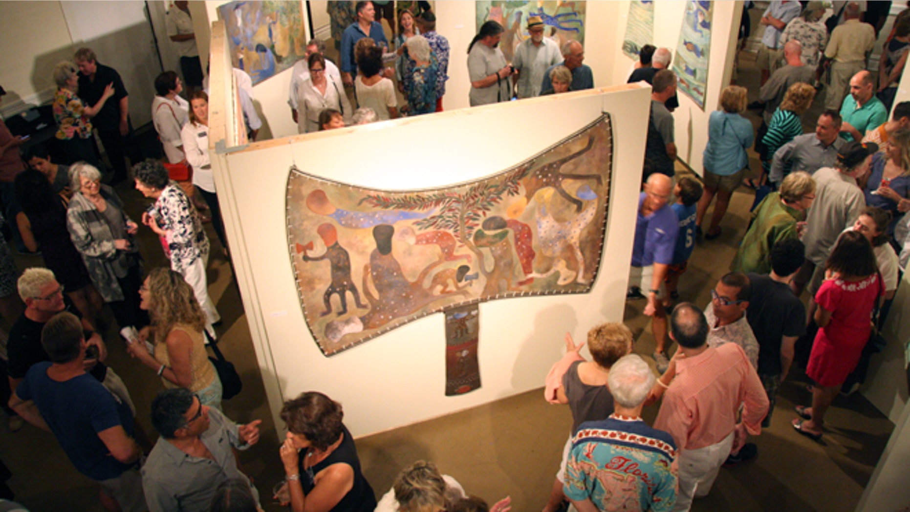 In this Thursday, Feb. 20, 2014 photo, patrons look at work by Cuban artist Manuel Mendive at the Studios of Key West in Key West, Fla. Mendive's work is on display as part of an exhibit that organizers say is the first exchange between Cuban and U.S. art museums in more than five decades. (AP Photo/Christine Armario)