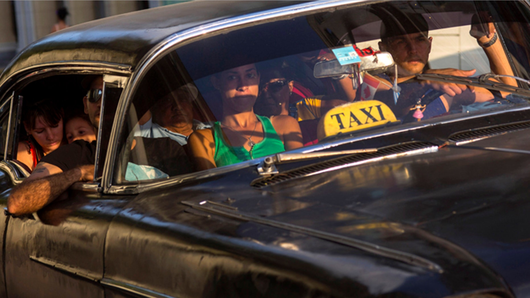 A taxi driver transports a car full of passengers, in Havana, Cuba, Tuesday, Feb. 17, 2015. A more relaxed and hopeful atmosphere is evident in Cuba as a result of President Raul Castroís modest reforms and afte the agreement by Cuba and the U.S. to move toward a more normal relationship. (AP Photo/Ramon Espinosa)