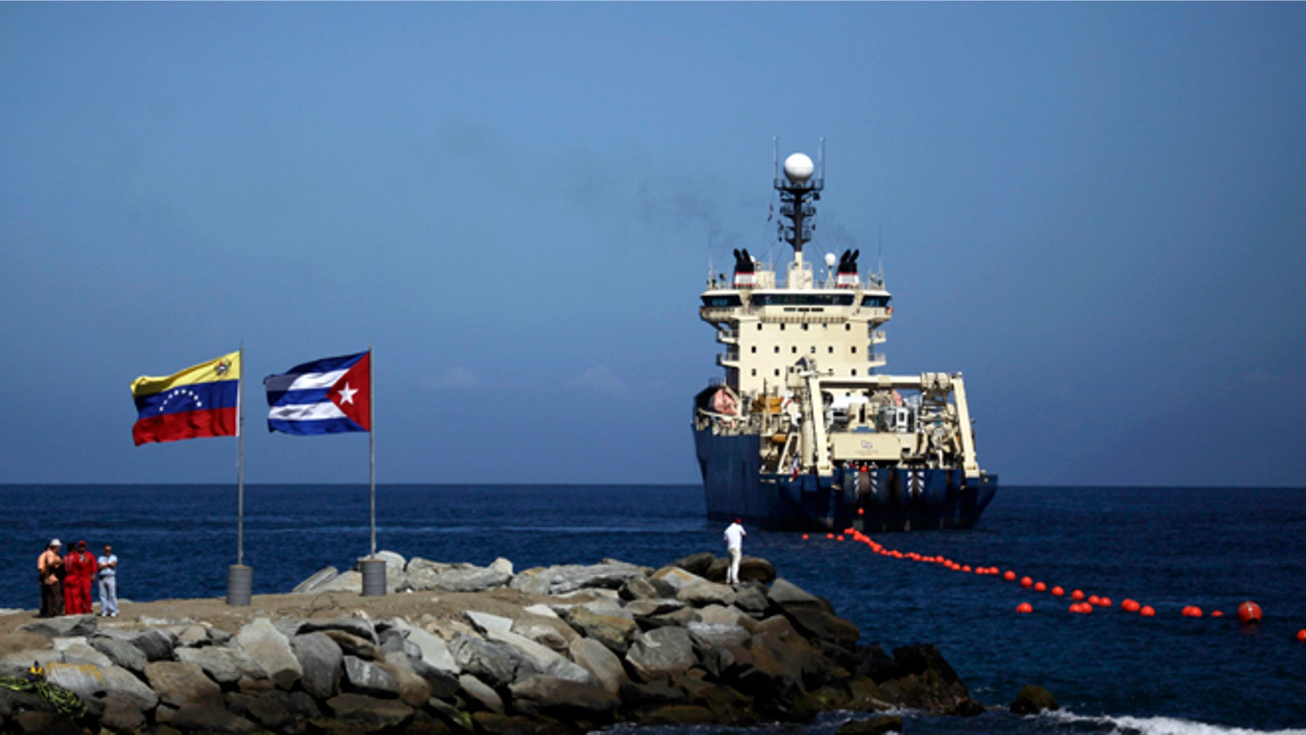 Jan. 22, 2011: {eople stand on a breakwater, with a Venezuelan flag, left, and a Cuban flag, as a specialized ship rolls out a fiber-optic cable, suspended from buoys, off La Guaira, Venezuelan coast. Cuba's state telecom monopoly confirmed Thursday, Jan. 24, 2013 that the island's first hard-wired Internet connection to the outside world has been activated, but said it won't lead to an immediate increase in access.