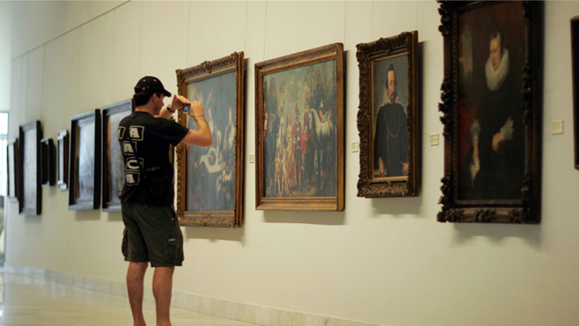 HAVANA - DECEMBER 01: A visitor photographs the paintings on display at the Fine Arts Museum December 1, 2006 in Havana, Cuba. (Photo by Joe Raedle/Getty Images)