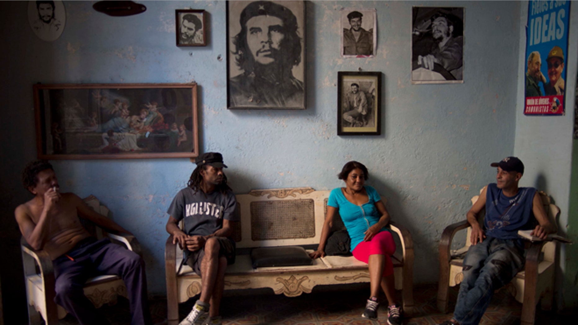 Roberto Alvarez, 47, right, chats with friends backdropped by a wall decorated with images of Cuban revolutionary heroes, Che Guevara, Fidel Castro and his brother, President Raul Castro, in Havana, Cuba, Wednesday, Feb. 25, 2015. Any kind of benefit for the Cuban people, thatll be hard. said Alvarez when asked if the negotiations with the US would help. (AP Photo/Ramon Espinosa)