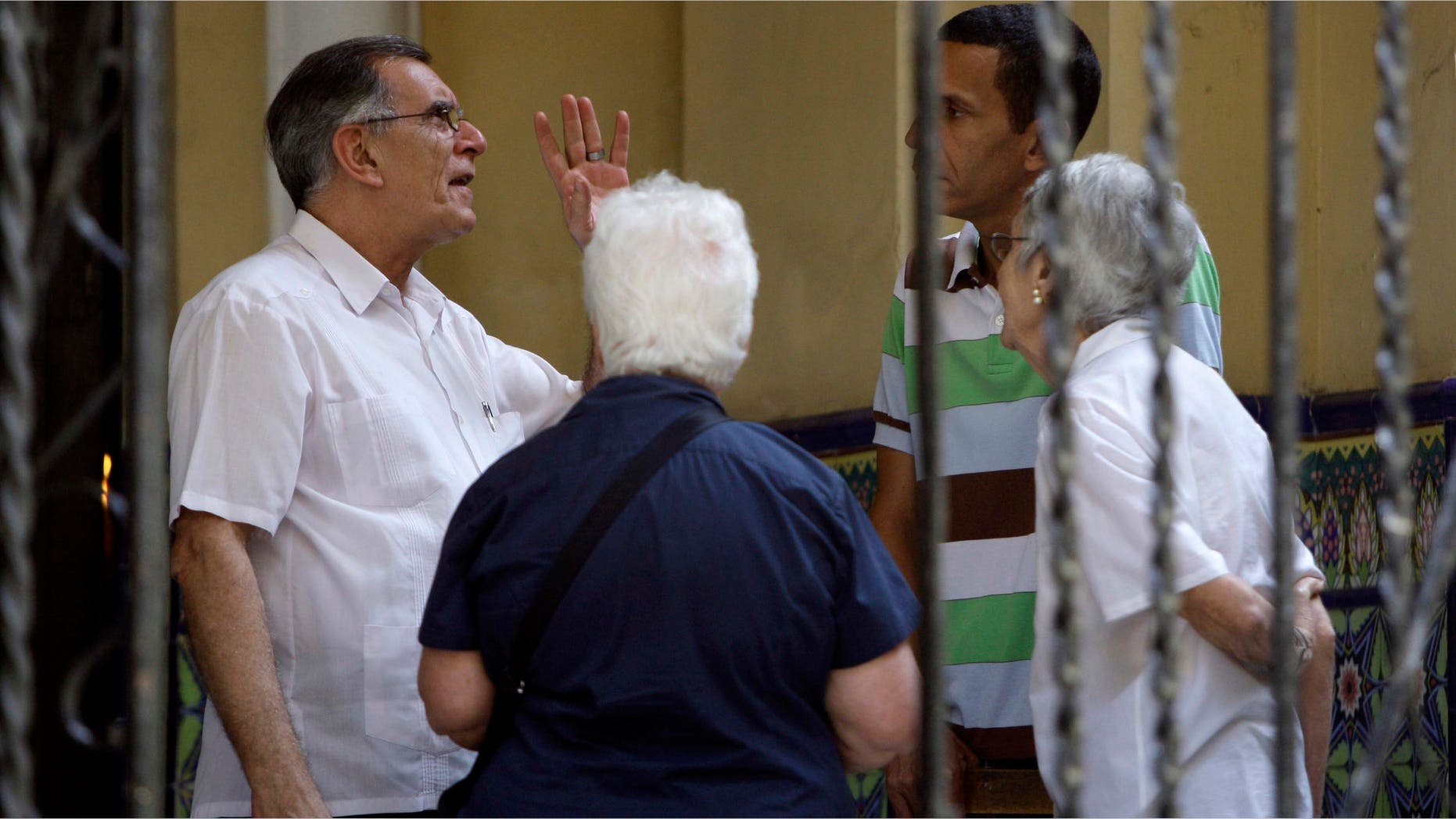 Roberto Betancourt, priest at the Virgin of Charity of Cobre Catholic church, left, speaks with unidentified people outside the church in Havana, Cuba, Thursday March 15, 2012. A group of Cuban dissidents who have occupied the church for two days are no longer demanding an audience with Pope Benedict XVI when he visits this month, but vowed Thursday to continue their protest. The dissidents say they are now asking the pontiff to mediate a list of their grievances with the Cuban government.