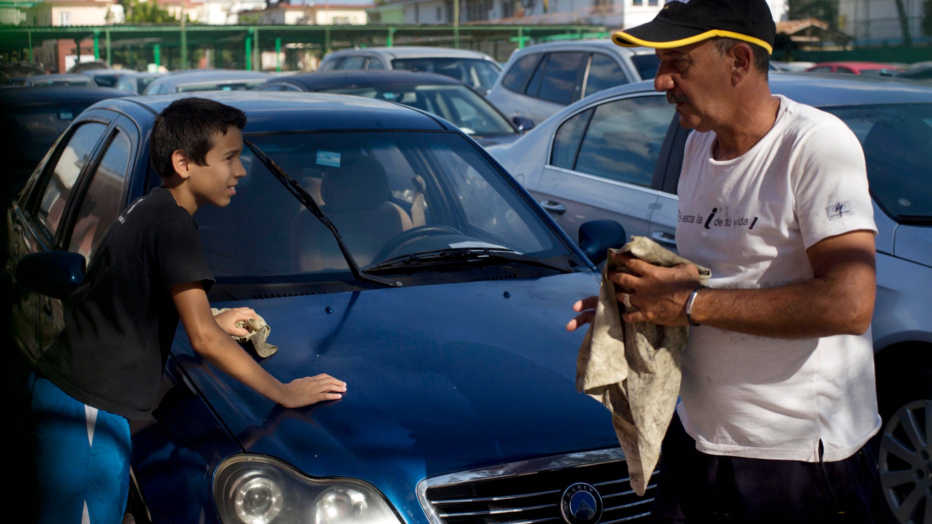 Jan. 2, 2014: A car dealership worker, right, and a boy clean a used Chinese Geely for sale at a government-run dealership in Havana, Cuba.