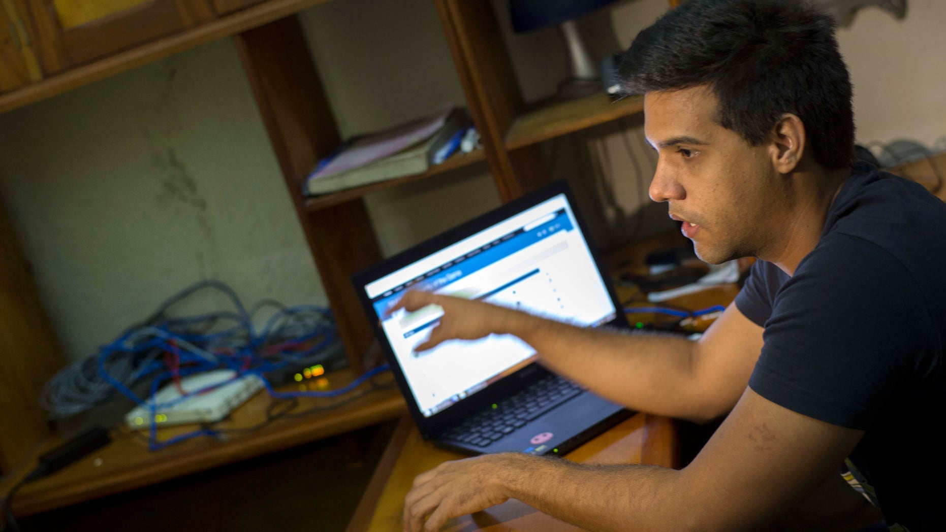 In this Jan. 4, 2015 photo, Rafael Antonio Broche Moreno talks during an interview with The Associated Press, next to his computer, modem and intranet network cabling at his home in Havana. Disconnected from the real Internet, the intranet network is limited, local and built with equipment commercially available around the world, with no help from any outside government, organizers say. (AP Photo/Ramon Espinosa)