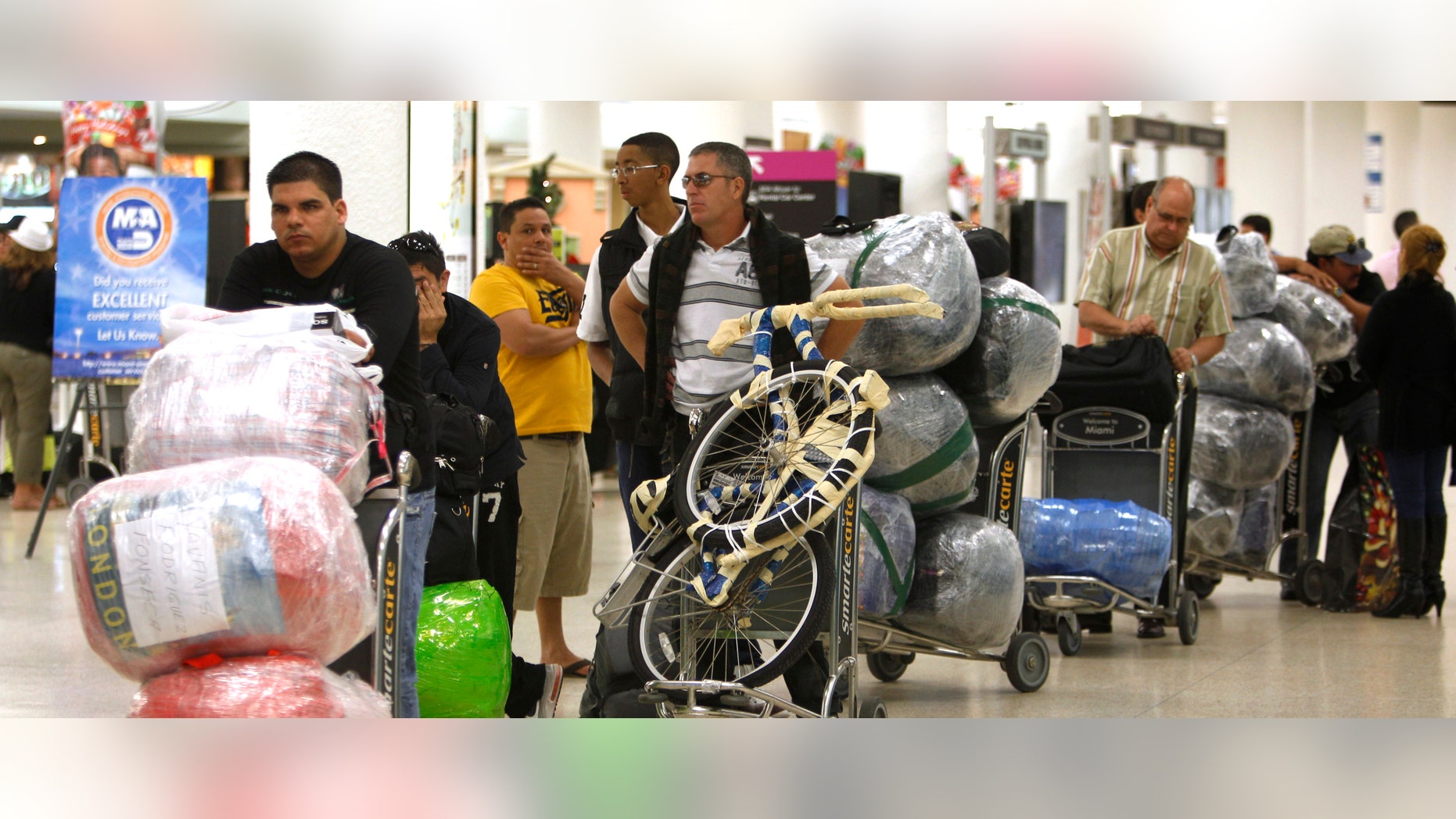 Travelers wait in line with their luggage at Miami International Airport before traveling Cuba, Monday, Dec. 19, 2011, in Miami. As the holidays approach this year, thousands of Cuban-Americans are taking advantage of the Obama administration's relaxed travel regulations to return to the island. (AP Photo/Lynne Sladky)