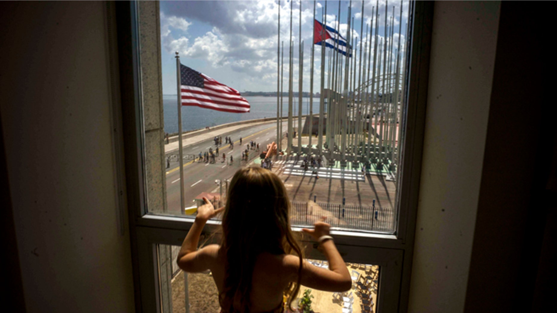 FILE - In this Aug. 14, 2015 file photo, a girl looks out from the newly opened U.S. Embassy after the U.S. flag raising ceremony in Havana, Cuba, as part of officially restored diplomatic relations. U.S. presidential candidate Donald Trump had been generally supportive of the normalization of relations with Cuba, but on Friday, Sept. 16, 2016 the Republican nominee pledged to reverse Obamas series of executive orders unless Cuba's President Raul Castro meets demands including religious and political freedom for the Cuban people and the freeing of political prisoners." (AP Photo/Ramon Espinosa, File)