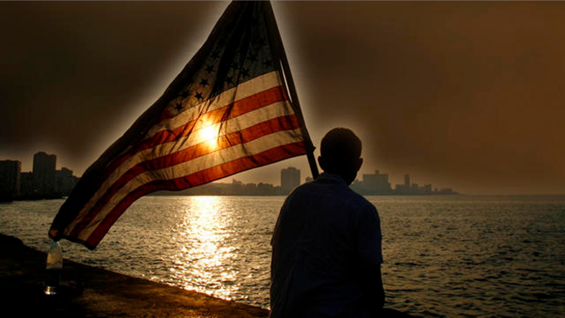 A Mexican-American , no name available, studying medical science in a Cuban university holds a U.S flag as he watches the sunset in Havana's Malecon after a march to commemorate the 136th anniversary of the execution of eight medicine students by the Spanish colonial government in Havana, Tuesday Nov.27, 2007. Thousands of Cuban medical science students marched to commemorate the event that took place during Cuba's war of Independence.(AP Photo/Javier Galeano)