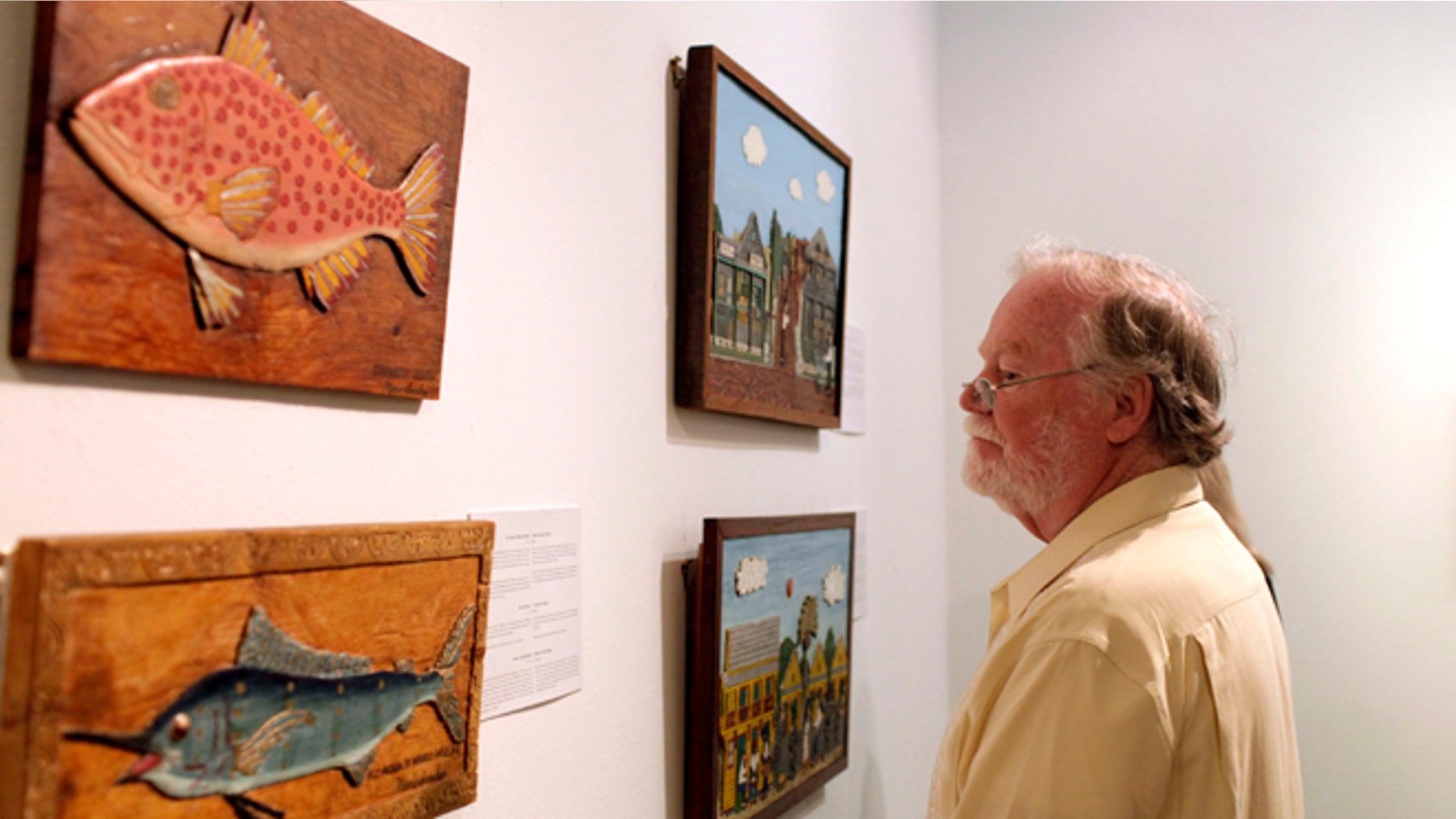 A man looks at art by Mario Sanchez, a deceased Florida artist of Cuban descent, inside the Bellas Artes museum in Havana, Cuba, late Friday, Jan. 17, 2014. The show, titled "Una Raza" or "One Race," is part of an exchange between Havana and Key West under which several prominent Cuban artists will exhibit on the Florida island next month. (AP Photo/Franklin Reyes)