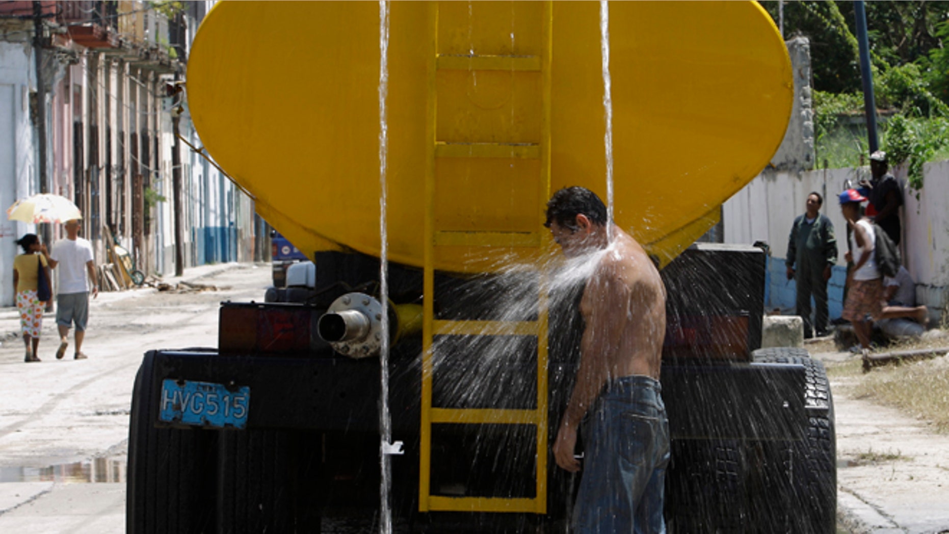 A man cools himself in water overflowing from a parked truck that delivers drinking water in Havana, Cuba, Wednesday, Aug. 21, 2013. The United States has issued an advisory for travelers to Cuba after several foreign visitors were sickened by cholera in recent weeks. "We urge you to follow public health recommendations and guidelines, such as safe food and water precautions and frequent hand washing to help prevent cholera infection," the diplomatic mission said in a statement published online. The embargo against Cuba bars most American tourism to the island, but hundreds of thousands of Cuban-Americans make legal family visits each year and increasing numbers of U.S. citizens are visiting through licensed cultural exchanges. (AP Photo/Franklin Reyes)