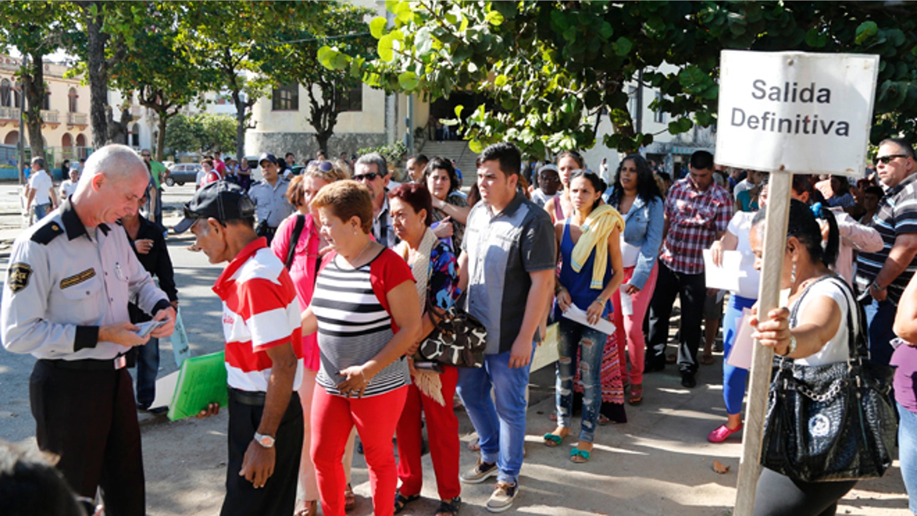 People queue for visas at the U.S. Interests Section in Havana, Cuba, Monday, Dec. 22, 2014. After the surprise announcement of the restoration of diplomatic ties between Cuba and the U.S., many Cubans expressed hope that it will mean greater access to jobs and the comforts taken for granted elsewhere, and lift their struggling economy. The sign on the post reads in Spanish "definite Exit." (AP Photo/Desmond Boylan)