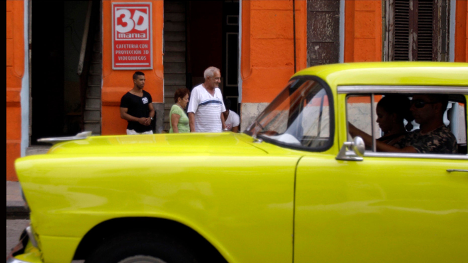 A classic American car that is used as a taxi passes by the entrance of a private movie theater called "3D Mania" in Havana, Cuba, Monday, Oct. 28, 2013. Cuban entrepreneurs have quietly opened dozens of backroom video salons over the last year, seizing on ambiguities in licensing laws to transform cafes and childrenâs entertainment parlors into a new breed of private business unforeseen by recent official openings in the communist economy. (AP Photo/Franklin Reyes)