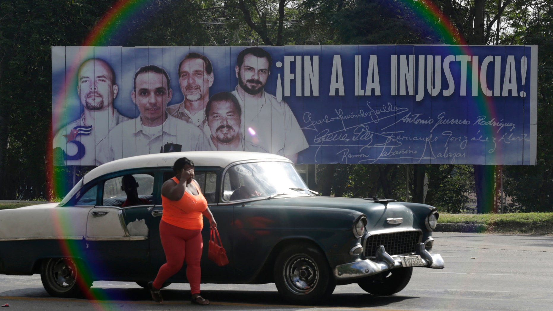 Dec. 17, 2014: A woman walks near a car in front of a banner featuring five Cuban prisoners held in U.S. custody, two of whom were previously released, in Havana.