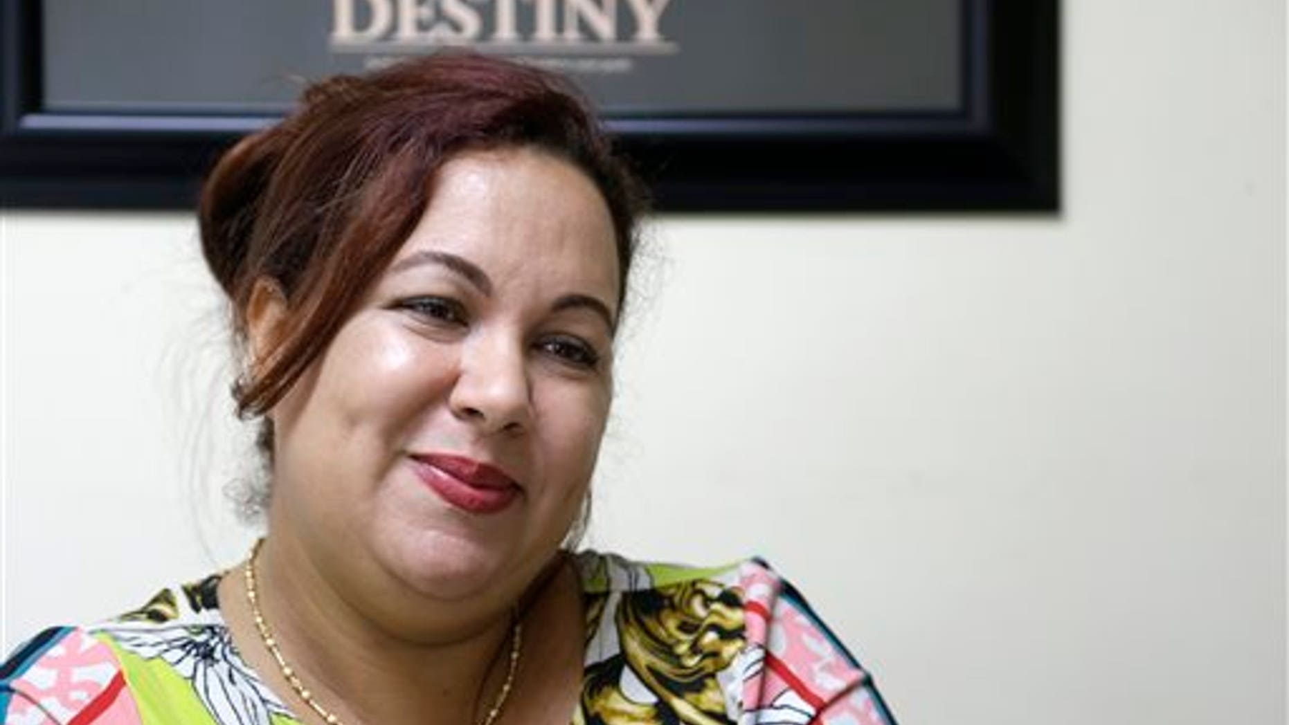 In this Sept. 19, 2013 photo, Irka Ducasse Blanes, a recent Cuban immigrant, smiles during an interview at a tax preparation office where she works in Miami. Since 2002, the number of Cubans leaving has hovered around 30,000 annually, making the last 10 years the largest exodus since the start of the revolution. The influx of new arrivals is evident throughout Miami, the heart of Cubas exile population. (AP Photo/Wilfredo Lee)
