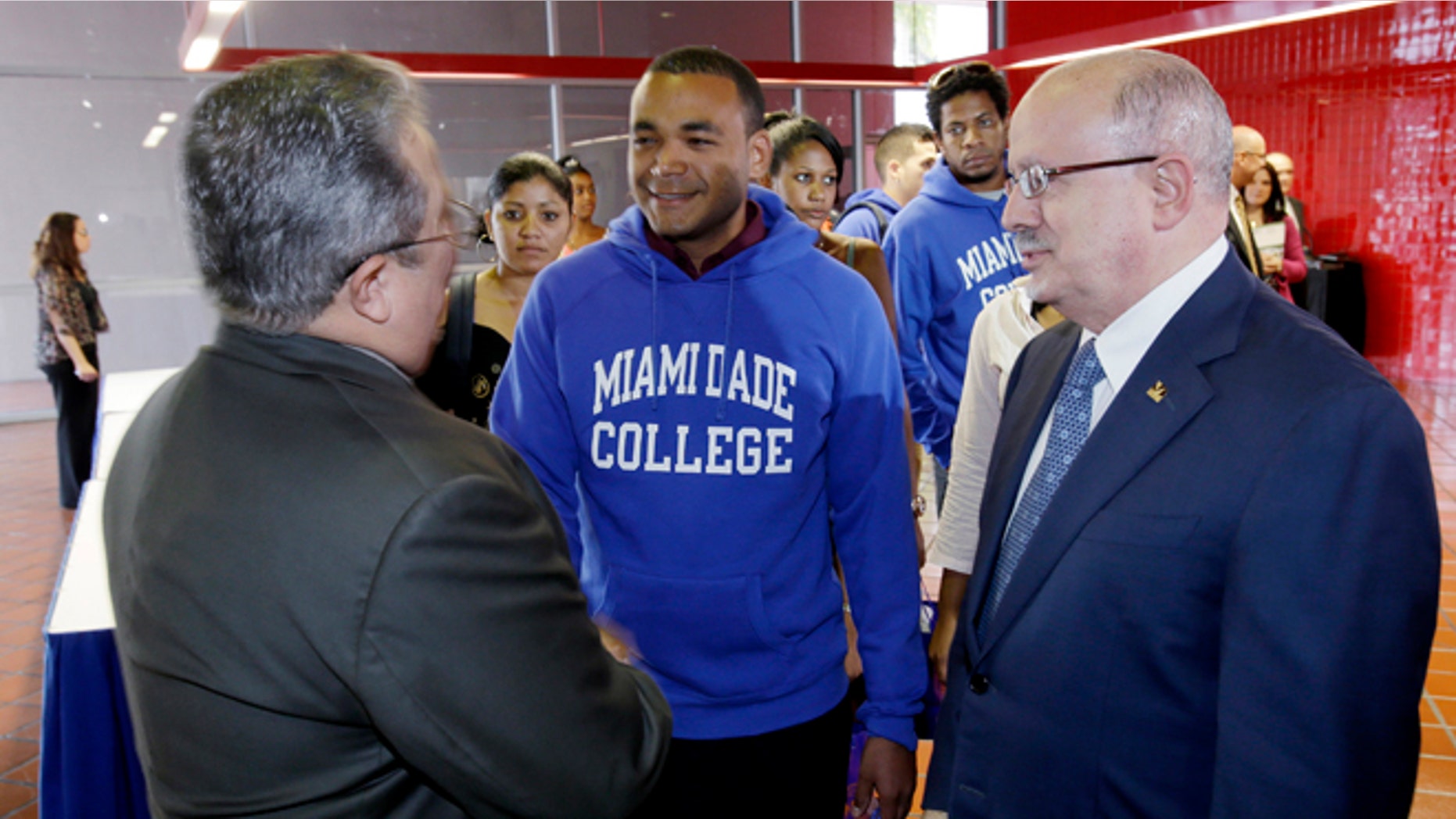 Victór Vazquez Hernández, left, Assistant Professor of the Social Science Department and Eduardo Padrón, right, president of Miami Dade College, greet students from Cuba as they arrive at a news conference, Monday, Jan. 13, 2014 for the announcement of their arrival at Miami Dade College in Miami. The group of students from Cuba is opening the communist country's first academic trip in more than five decades to the largest public college in Miami. (AP Photo/Wilfredo Lee)