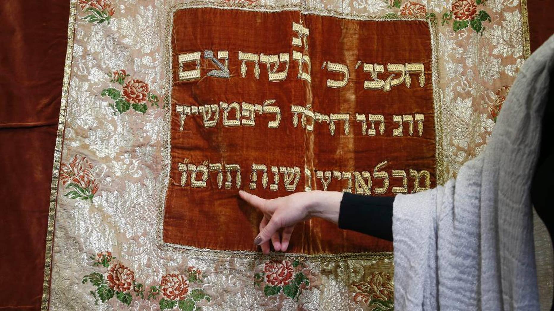 Visual arts curator of Jewish Museum in Prague Michaela Sidenberg points to details on a synagogue textile in Prague, Czech Republic, Wednesday, March 26, 2014. This textile stolen by the Nazis during the World War II has returned to the Czech Republic after it has been found in the United States. It is for the first time that a ritual Jewish property that was stolen during the Holocaust has been traced abroad and returned home. (AP Photo/Petr David Josek)