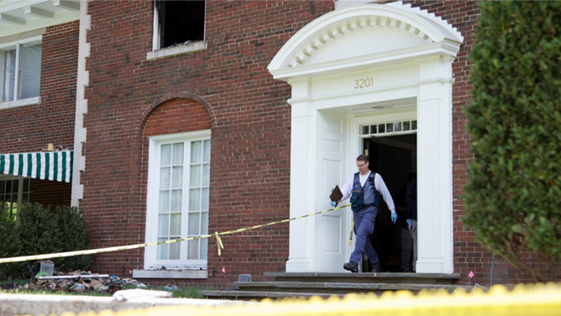 A Bureau of Alcohol, Tobacco, Firearms and Explosives investigator walks out of the fire-damaged multimillion-dollar home in northwest Washington, Wednesday, May 20, 2015, where four people were found dead May 14. Police issued a news release late Wednesday saying they are looking for a man identified as Daron Dylon Wint in connection with last Thursday's quadruple homicide. (AP Photo/Manuel Balce Ceneta)