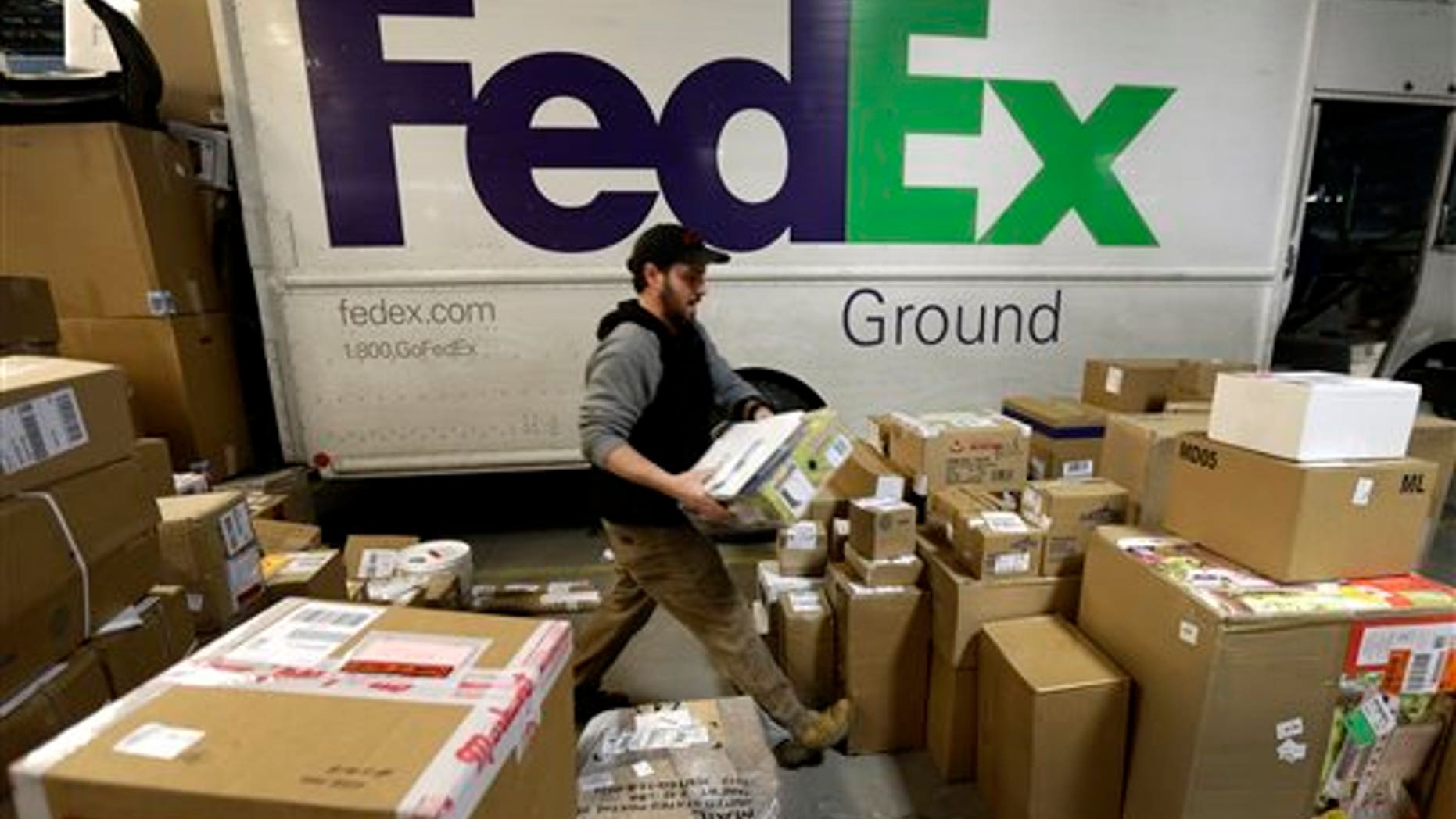 FILE - In this Dec. 16, 2013 file photo, package handler Chris Addison arranges packages before loading a delivery truck at a FedEx sorting facility in Kansas City, Mo. Santa's sleigh didn't make it in time for Christmas for some this year due to shipping problems at UPS and FedEx.The delays were blamed on poor weather earlier this week in parts of the country as well as overloaded systems. (AP Photo/Charlie Riedel)