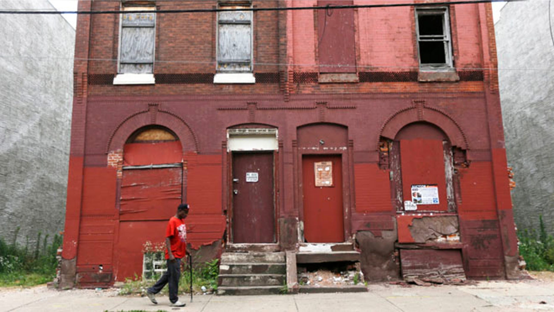 FILE - In this July 11, 2013 file photo a man walks through a blighted neighborhood in Philadelphia. Democrats are set to begin their convention Monday, July 25, 2016, in a city that symbolizes both the nation's promise and its shortcomings. (AP Photo/Matt Rourke, File)