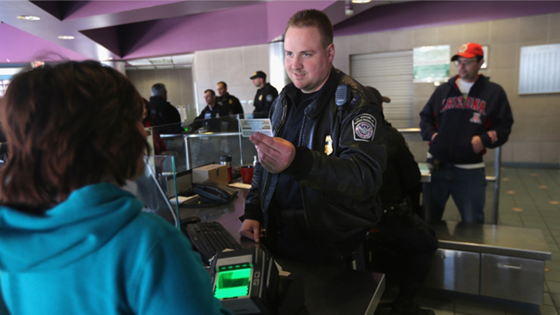 NOGALES, AZ - FEBRUARY 26: Officer Joe Sokolowski from the Office of Field Operations (OFO) checks identifications at a port of entry from Mexico into the United States on February 26, 2013 in Nogales, Arizona. Some 15,000 people cross between Mexico and the U.S. each day in Nogales, Arizona's busiest border crossing. (Photo by John Moore/Getty Images)