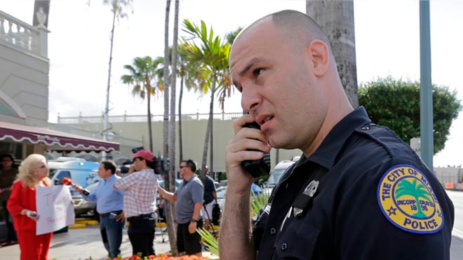 City of Miami police officer R. Delgado covers his badge with a black band as he honors the death of police officers in Dallas, Friday, July 8, 2016, at a Republican presidential candidate Donald Trump campaign stop. Trump has called off his two Friday campaign events in Miami in the wake of deadly sniper killings of Dallas police officers. (AP Photo/Alan Diaz)