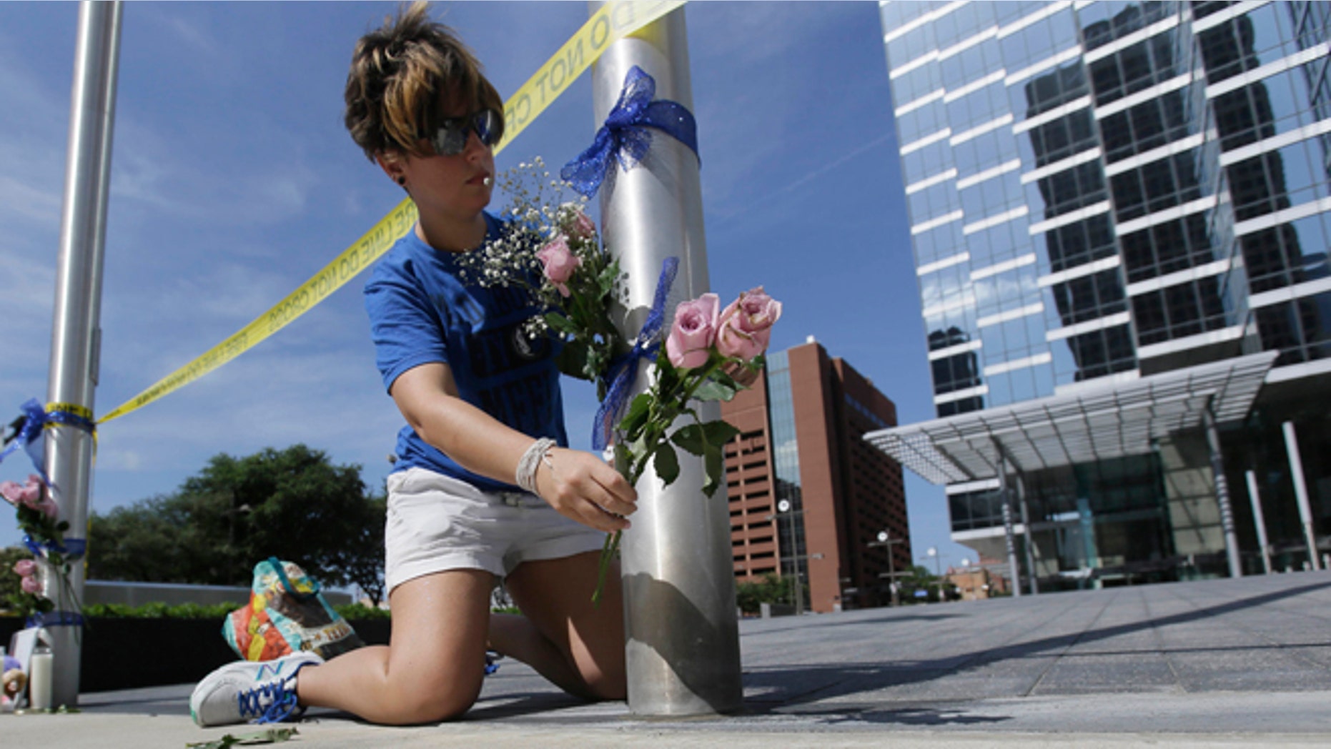 Noelle Hendrix places flowers near the scene of a shooting in downtown Dallas, Friday, July 8, 2016. Snipers opened fire on police officers in the heart of Dallas during protests over two recent fatal police shootings of black men. (AP Photo/LM Otero)