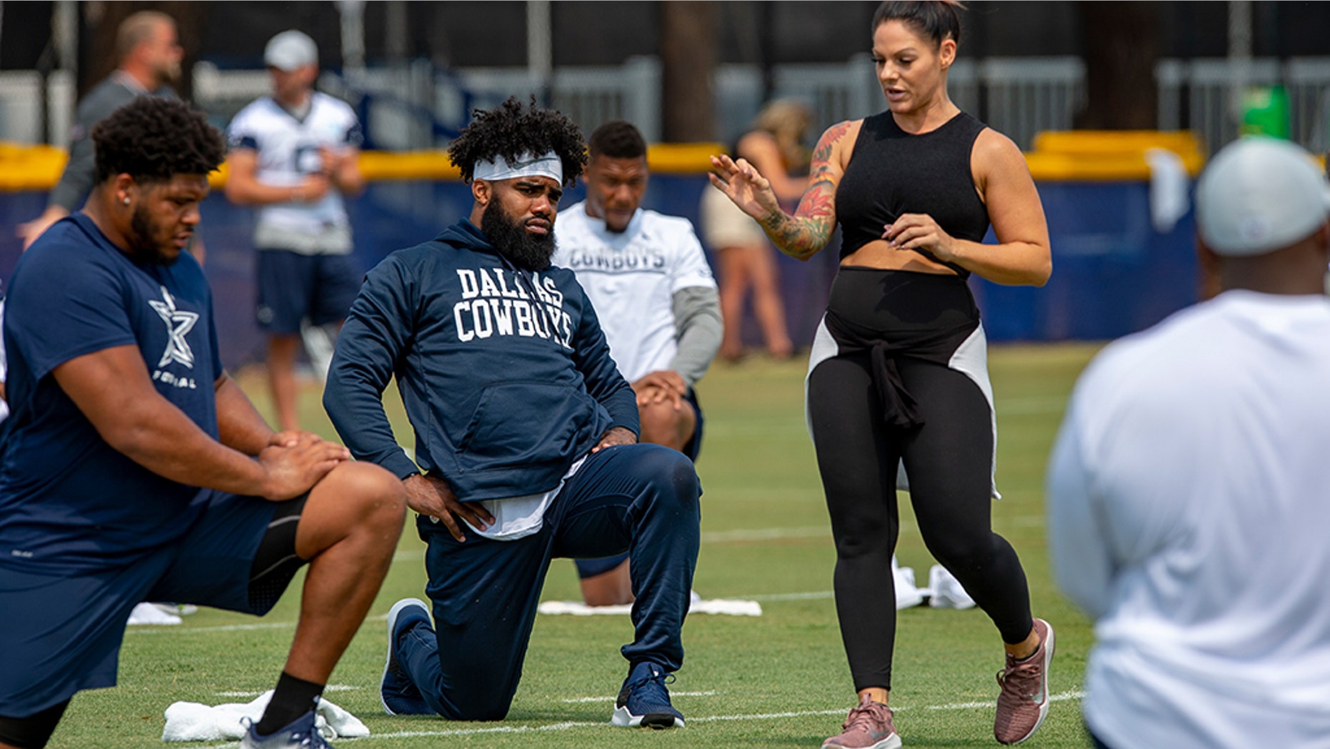 FILE - In this July 28, 2018, file photo, Dallas Cowboys offensive tackle La'el Collins, left and running back Ezekiel Elliott, center, listen to yoga instructor Stacey Hickman, right, as the team does some flexibility exercises at NFL football training camp in Oxnard, Calif. (AP Photo/Gus Ruelas, File)
