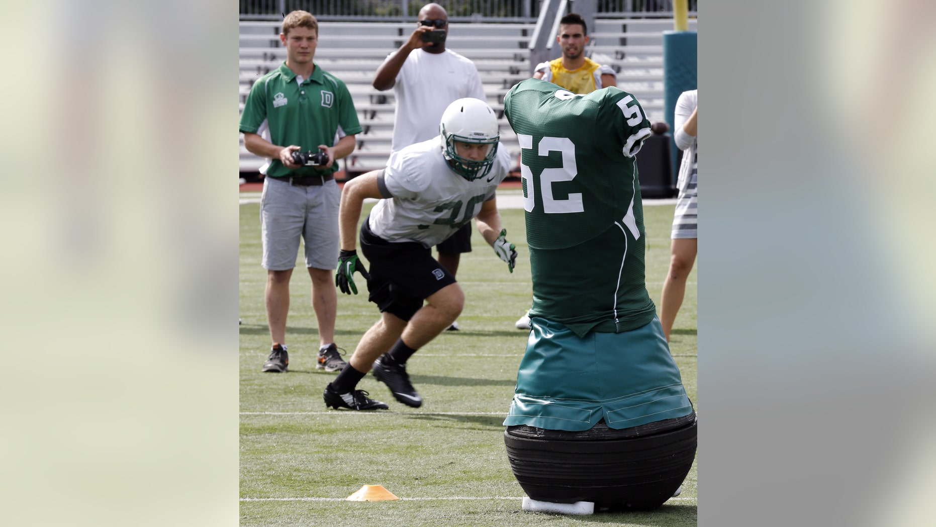Dartmouth College Engineering graduate Quinn Connell, upper left, controls the movement of the team's Mobile Virtual Player during college football practice Wednesday Aug. 26, 2015.