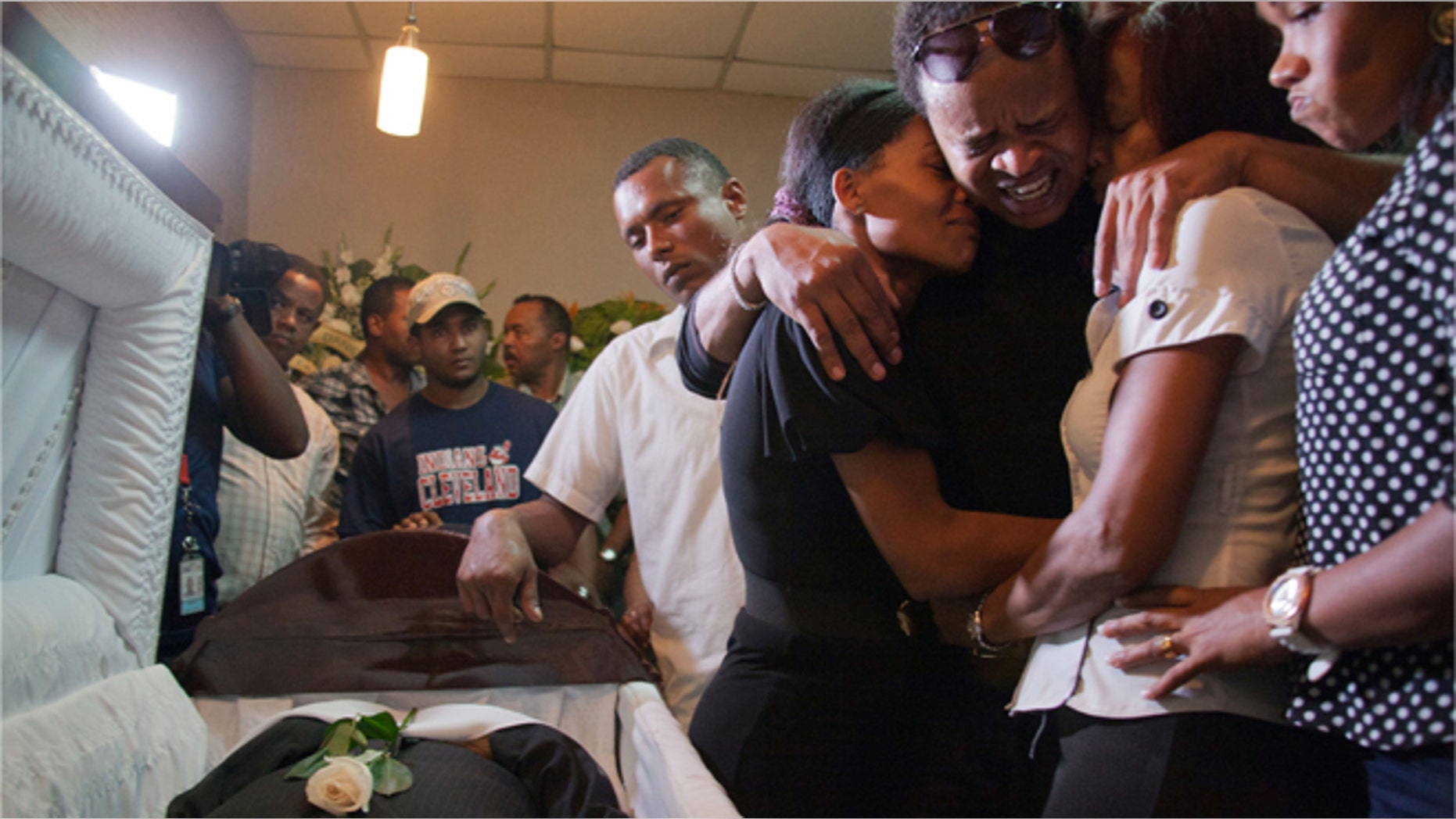 Kansas City Royals player Edinson Volquez, third from Right, embraces his sister Wendy Volquez, left, and mother Ana Ramirez as they stand next to the body of his father during his wake at a funeral home in Santo Domingo, Dominican Republic, Wednesday, Oct. 28, 2015. (AP Photo/Tatiana Fernandez)