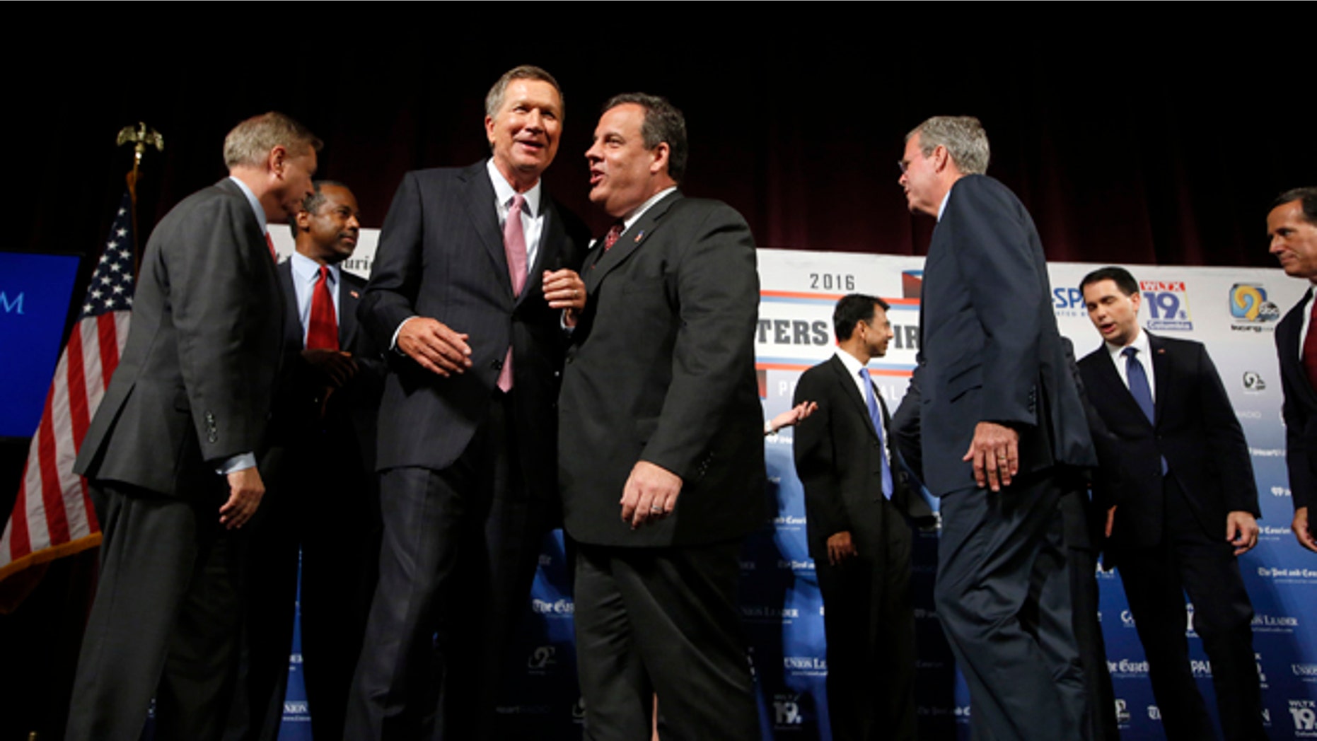 Republican presidential candidates, from left, Lindsey Graham, Ben Carson, John Kasich, Chris Christie, Bobby Jindal, Jeb Bush, Scott Walker and Rick Santorum speak among themselves after a forum Monday, Aug. 3, 2015, in Manchester, N.H. (AP Photo/Jim Cole)