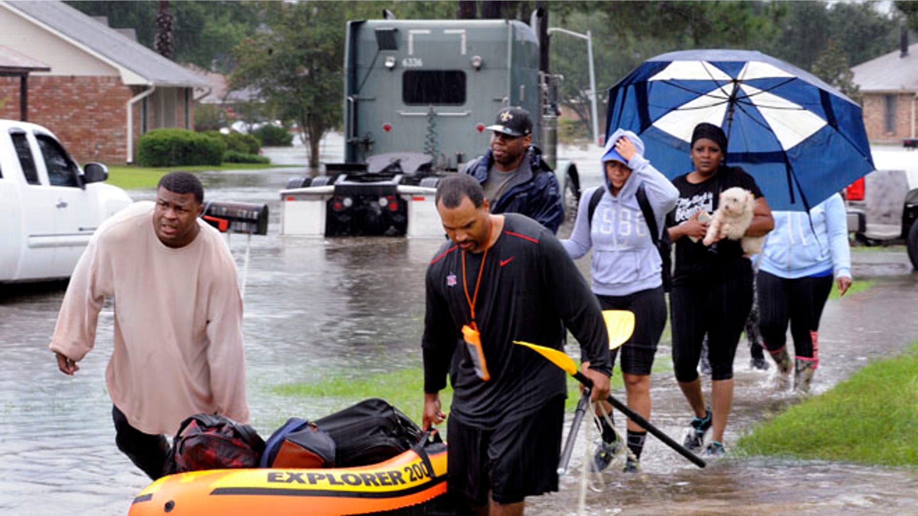 Residents use a raft to evacuate as others walk out of their neighbor Saturday, Aug. 13, 2016, in Baton Rouge, La.