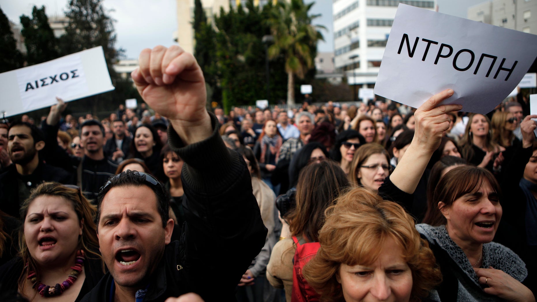FILE- In this Tuesday, March 26, 2013 file photo, employees of the Bank of Cyprus shout slogans as they holds banners reading in Greek "shame" during a protest at Cyprus central bank in Nicosia, Cyprus. The moment word broke that Cypriot lawmakers in Parliament had voted down a bailout deal that would have raided everyone's savings to prop up a collapsing banking sector, a huge cheer rose up from hundreds of demonstrators gathered outside that echoed through the building's corridors. Many relished it as a kind of David-against-Goliath moment a country of barely a million people standing up to the will of Europe's behemoths who wanted it to swallow a very bitter pill to fix its broken-down economy. (AP Photo/Petros Karadjias, File)