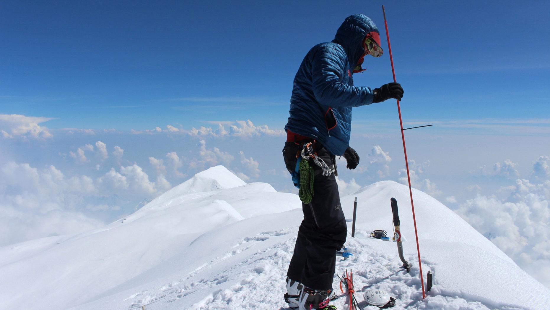 In this June 24, 2015, photo provided by Compass Data/USGS, Blaine Horner of CompassData probes the snow pack at the highest point in North America along with setting up Global Position System equipment for precise summit elevation data on top of Denali in Denali National Park, Ak.
