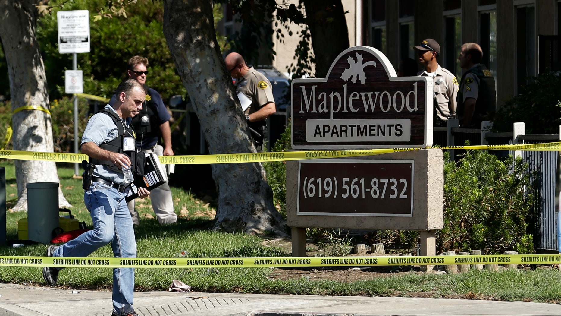 Sept. 25, 2012: A police official walks past the Maplewood Apartments after a shooting in Lakeside, Calif.