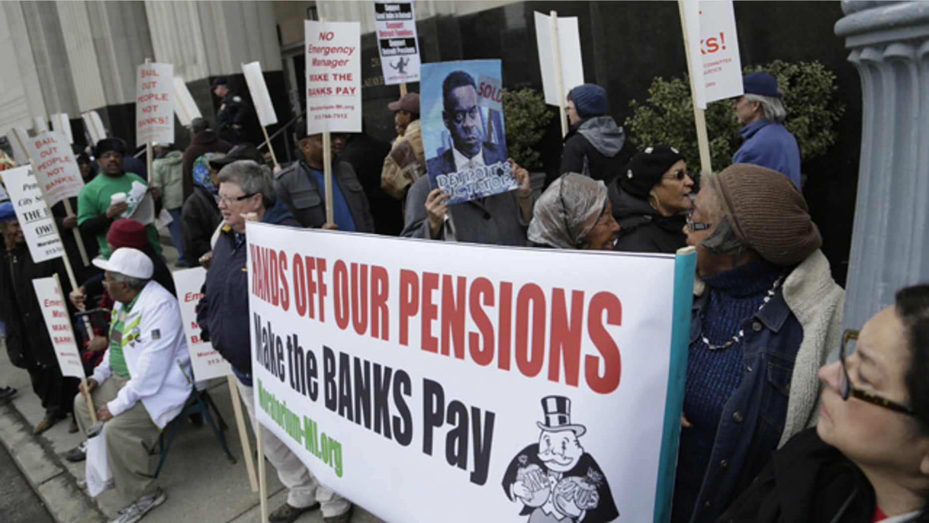 April 1, 2014: Protestors against deeper cuts in pensions march in front of the Theodore Levin Federal Courthouse in Detroit. (AP Photo/Detroit Free Press, Mandi Wright, File)