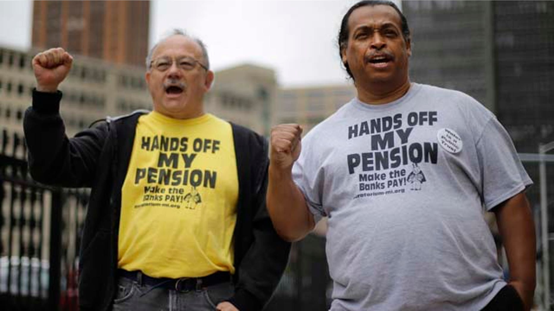 FILE - In a Thursday, July 3, 2014 file photo, Detroit retirees Mike Shane, left, and William Davis protest near the federal courthouse in Detroit. (AP Photo/Paul Sancya, File)
