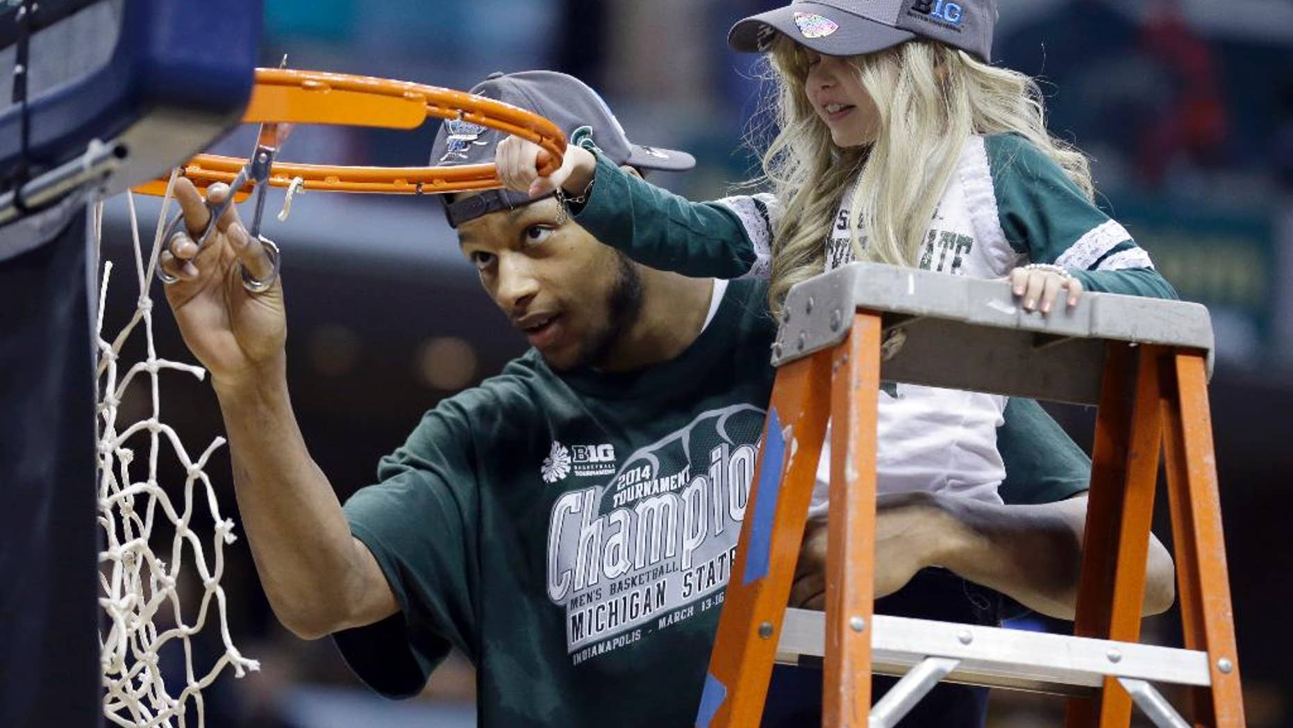 In this March 16, 2014, file photo, Michigan State forward Adreian Payne, left, cuts the net with Lacey Holsworth. Holsworth died in April 2014, after a battle with nerve-cell cancer. (AP Photo/Michael Conroy, File)
