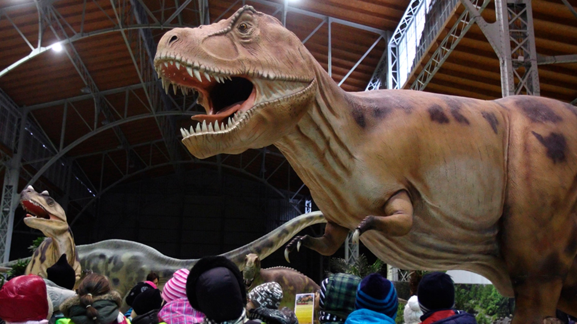 Children watch a life-sized Tyrannosaurus Rex dinosaur model in Vienna Feb. 7, 2014.