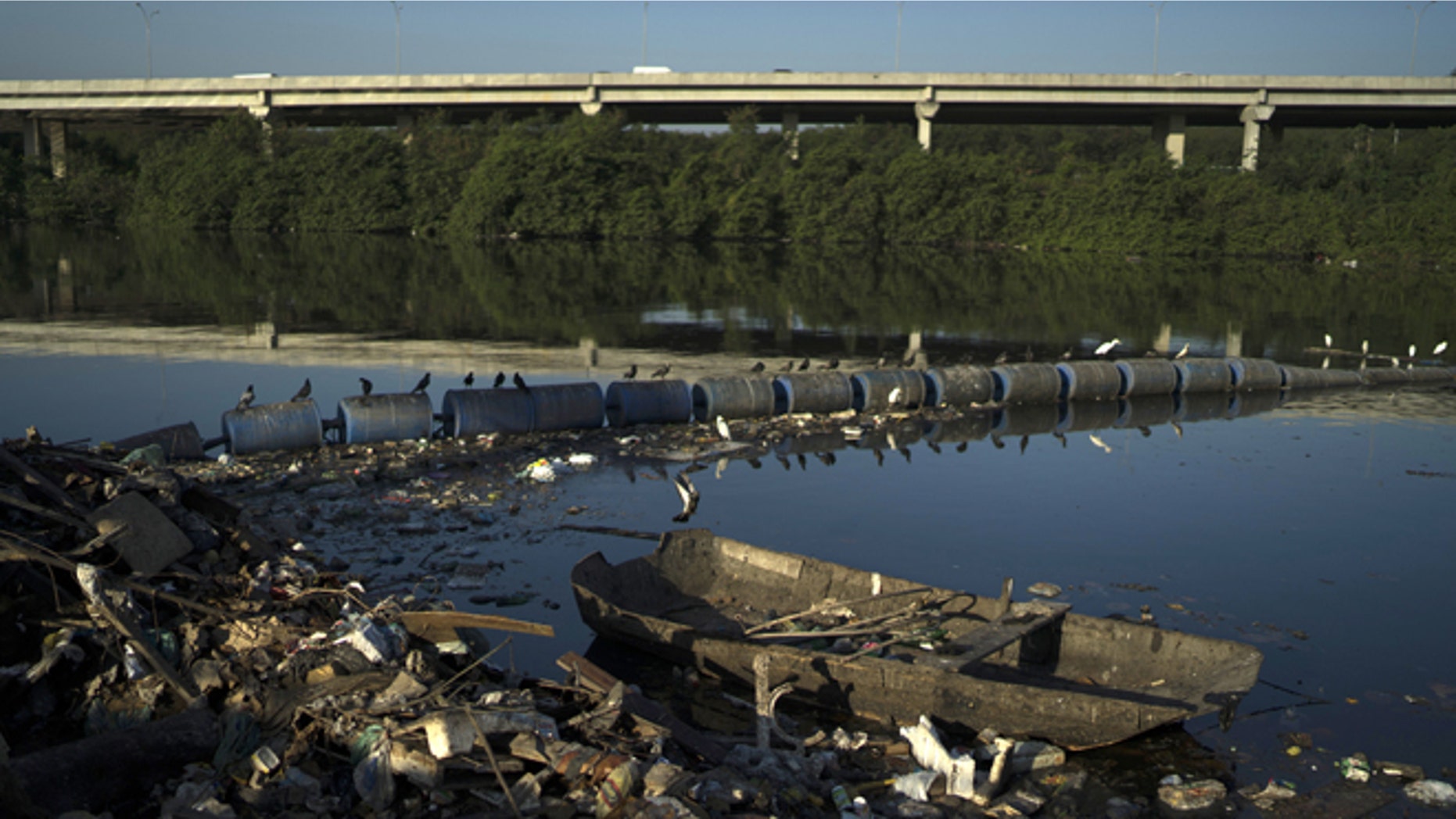 A discarded boat and trash abut floating waste barriers in a canal at the Mare slum complex, in Rio de Janeiro, Brazil, Friday, July 31, 2015. Rio's historic sewage problem spiraled over the past decade as the population exploded with many of the metropolitan area's 12 million residents settling in the vast slums that ring the bay. Waste flows into over 50 streams that empty into the once-crystalline Guanabara Bay. (AP Photo/Leo Correa)