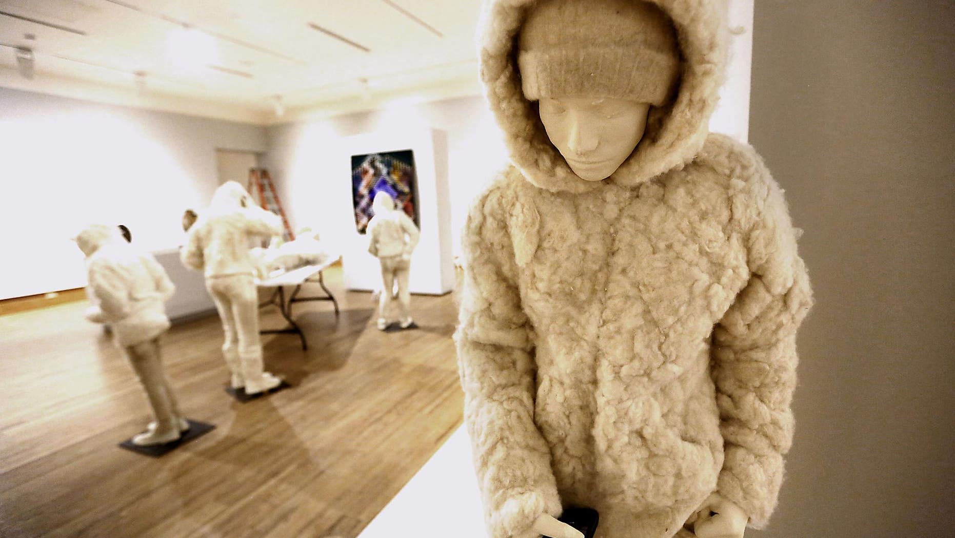People paying attention to their smartphones is one of the art pieces featured in the exhibit "Extreme Fibers: Textile Icons and the New Edge" at the Dennos Museum Center in Traverse City, Mich.