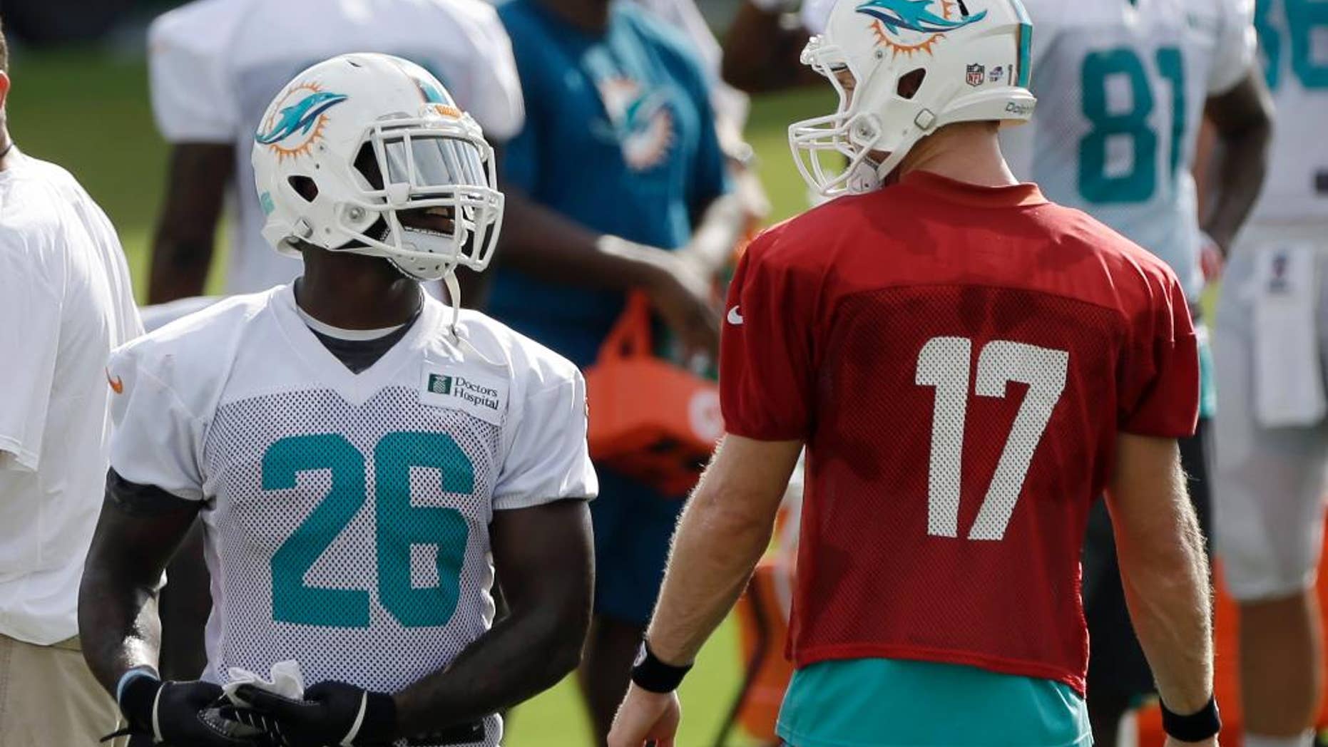 Miami Dolphins running back Lamar Miller (26) talks to quarterback Ryan Tannehill (17) during NFL football training camp in Davie, Fla., Wednesday, July 30, 2014. (AP Photo/Alan Diaz)