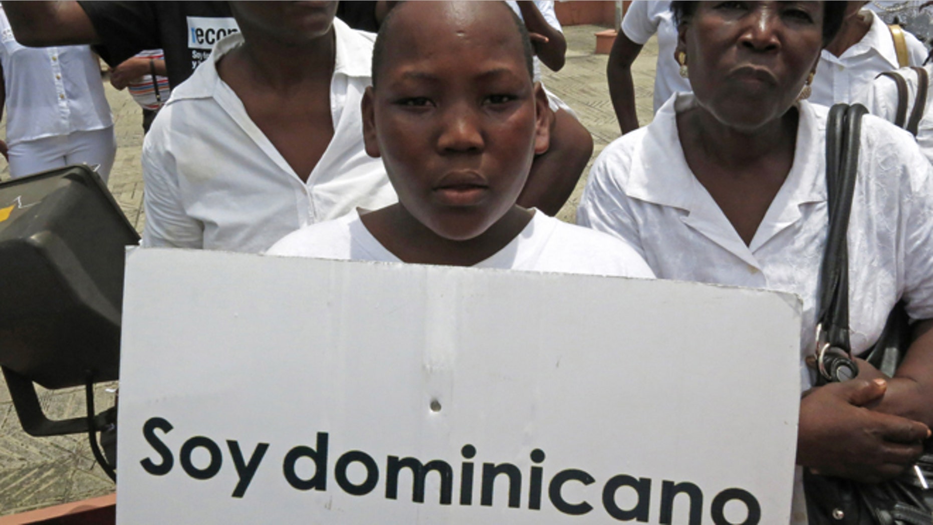 FILE - In this Aug. 12, 2013 file photo, a youth of Haitian descent holds a sign that reads in Spanish "I'm Dominican" during a protest demanding that President Danilo Medina stop the process to invalidate their birth certificates after authorities retained their ID cards, in Santo Domingo, Dominican Republic. The Dominican Republic's top court on Thursday, Sept. 26, 2013 stripped citizenship from thousands of people born to migrants who came illegally, a category that overwhelmingly includes Haitians brought in to work on farms. The decision cannot be appealed, and it affects all those born since 1929. (AP Photo/Ezequiel Abiu Lopez, File)